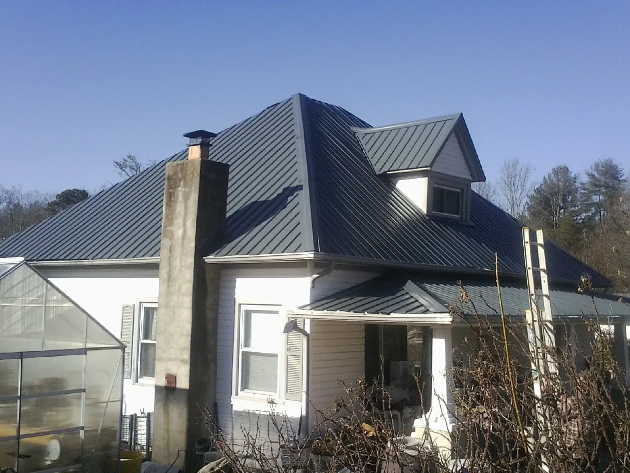 Dark blue standing seam metal roof on a white farmhouse with dormer — Slate & Tile Roof Repair by Roofing Brothers in Salt Lake City