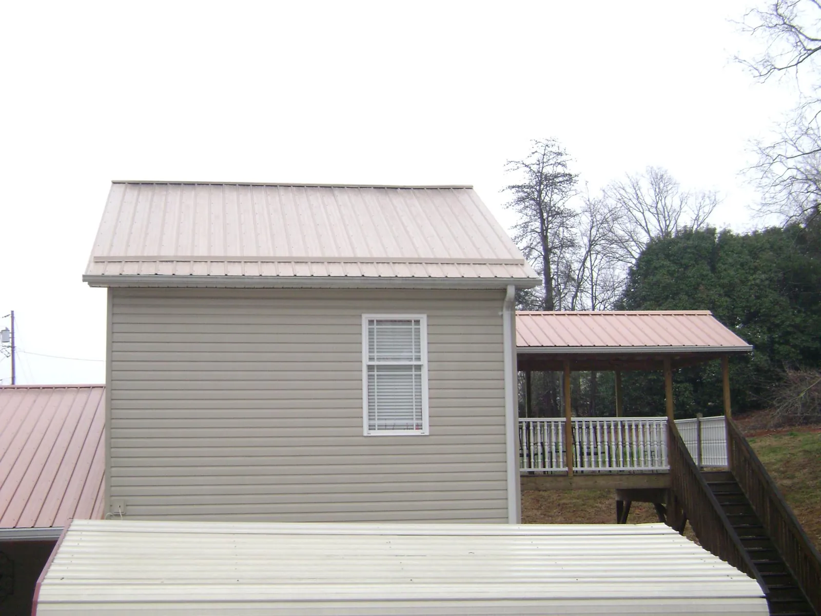 Tan metal roofs on a two story addition and attached porch, from a Roof Replacement job in Salt Lake City