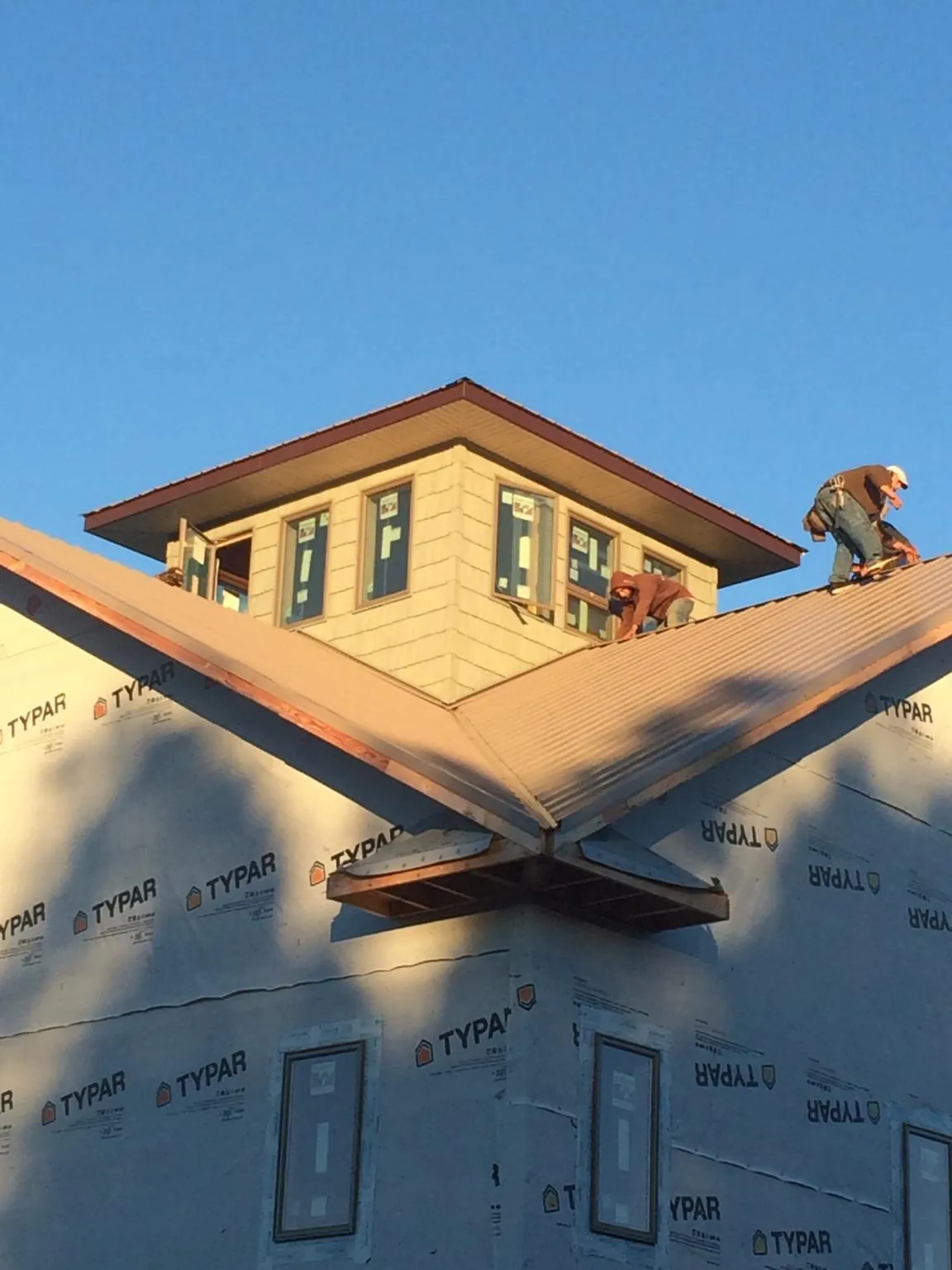 Roofers working around a rooftop cupola on a new metal roof at sunset — Roof Waterproofing in Salt Lake City by Roofing Brothers